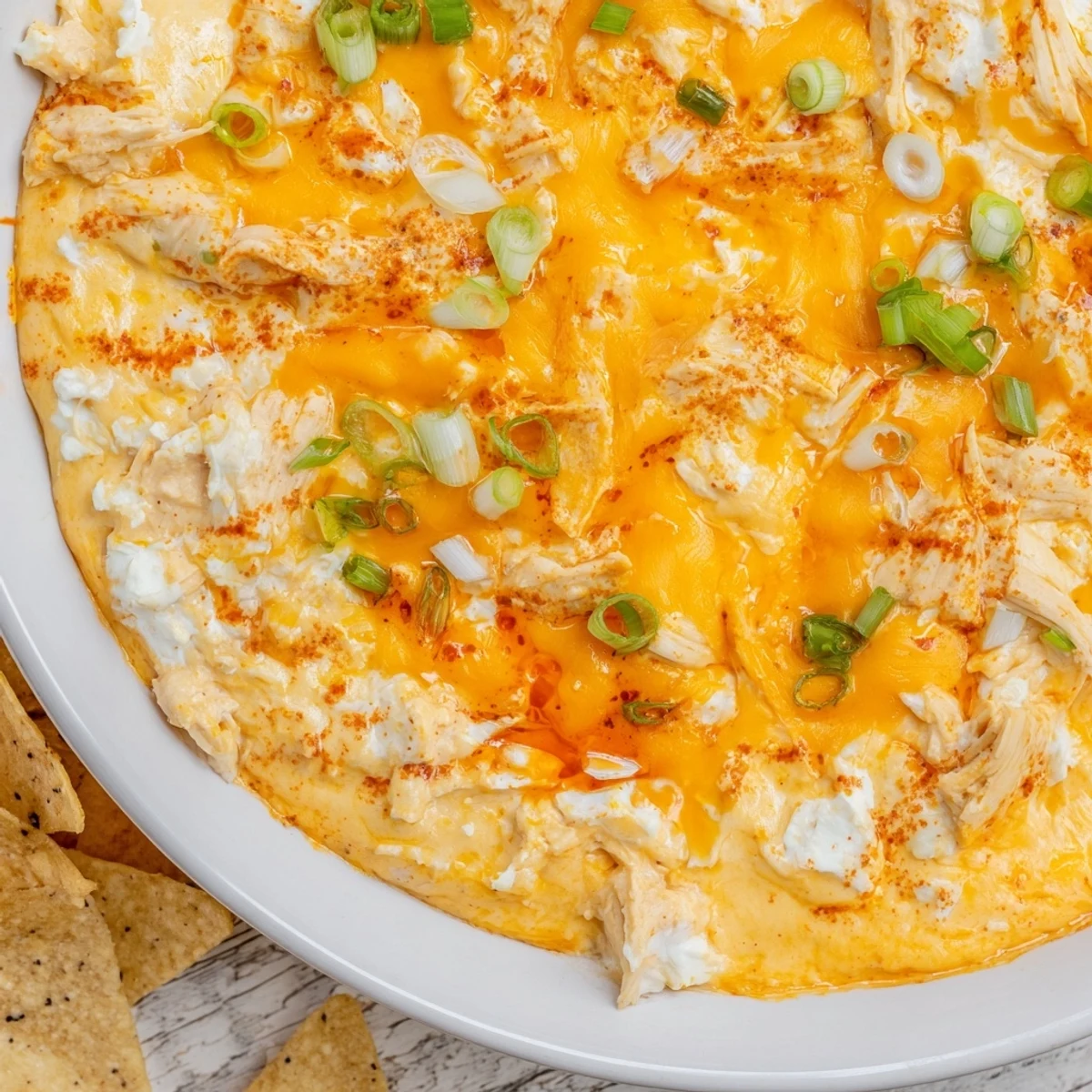 A close-up shot of creamy Spicy Buffalo Chicken Dip, garnished with green onions and ready to serve.