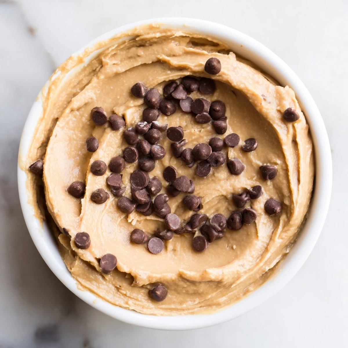 A close-up of delicious Chocolate Chip Cookie Dough Hummus, with a spoon revealing its smooth texture.