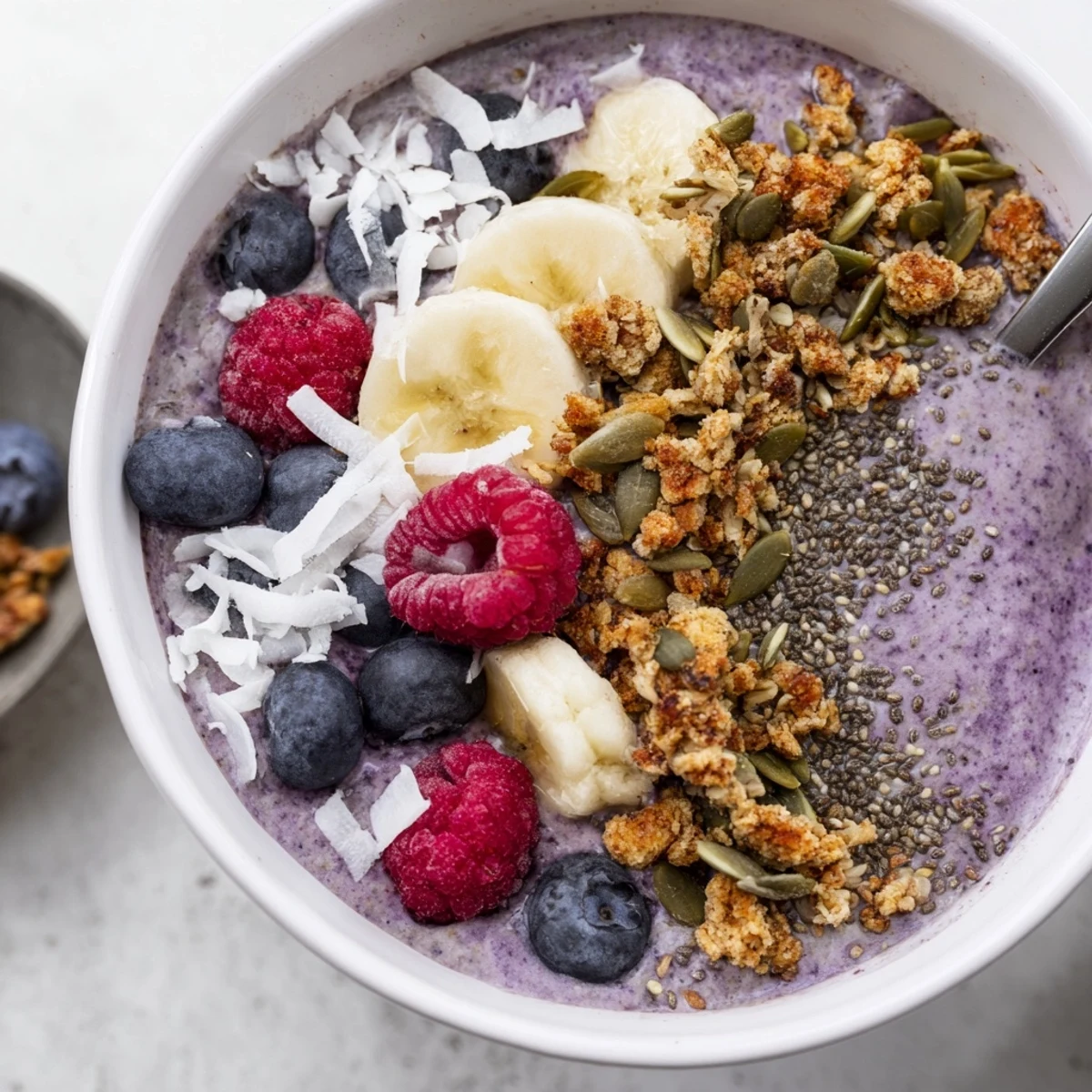 A vibrant Winter Berry Smoothie Bowl with chia seeds is topped with granola and fresh berries, offering a creamy, antioxidant-rich breakfast.