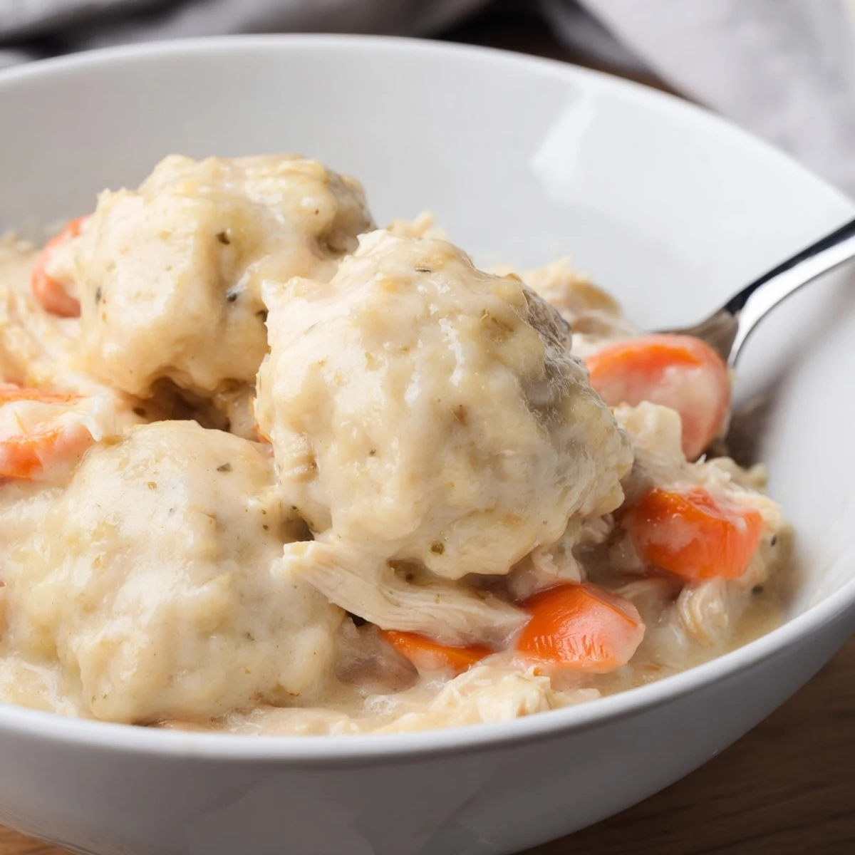 Tender shredded chicken, fluffy dumplings, and bright orange carrots in creamy broth.