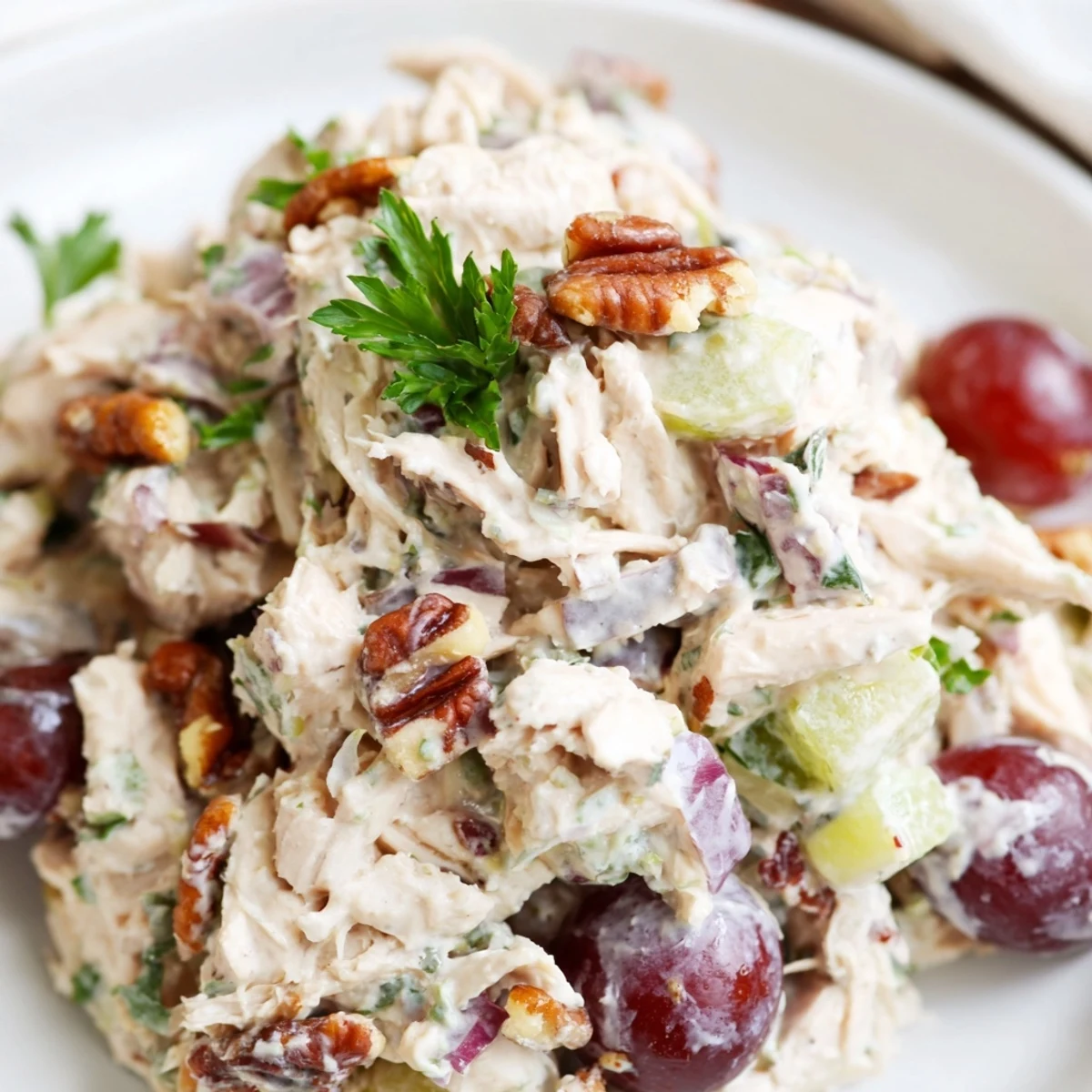 Freshly made Chicken Pecan Salad in a white bowl, featuring tender chicken, toasted pecans, celery, and red grapes coated in creamy dressing.