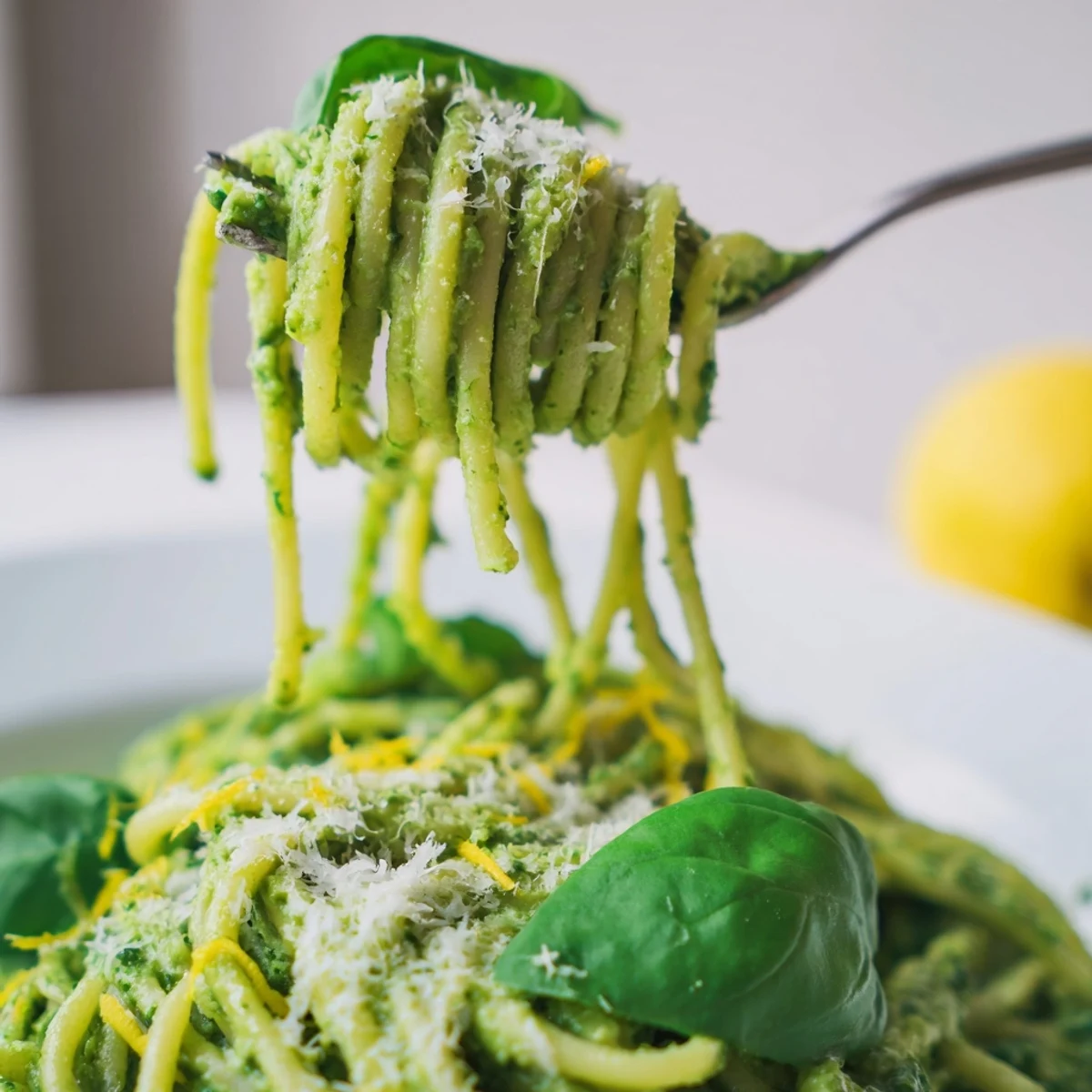 A generous bowl of creamy avocado and spinach spaghetti features silky green sauce, lemony aroma, and a hearty Italian-inspired serving.