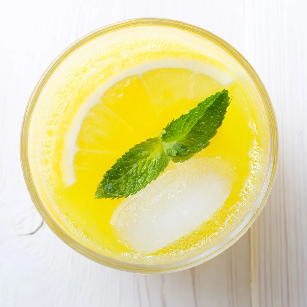A close-up of Lemon Juice with Sugar in a chilled glass, condensation on the side, garnished with fresh mint.