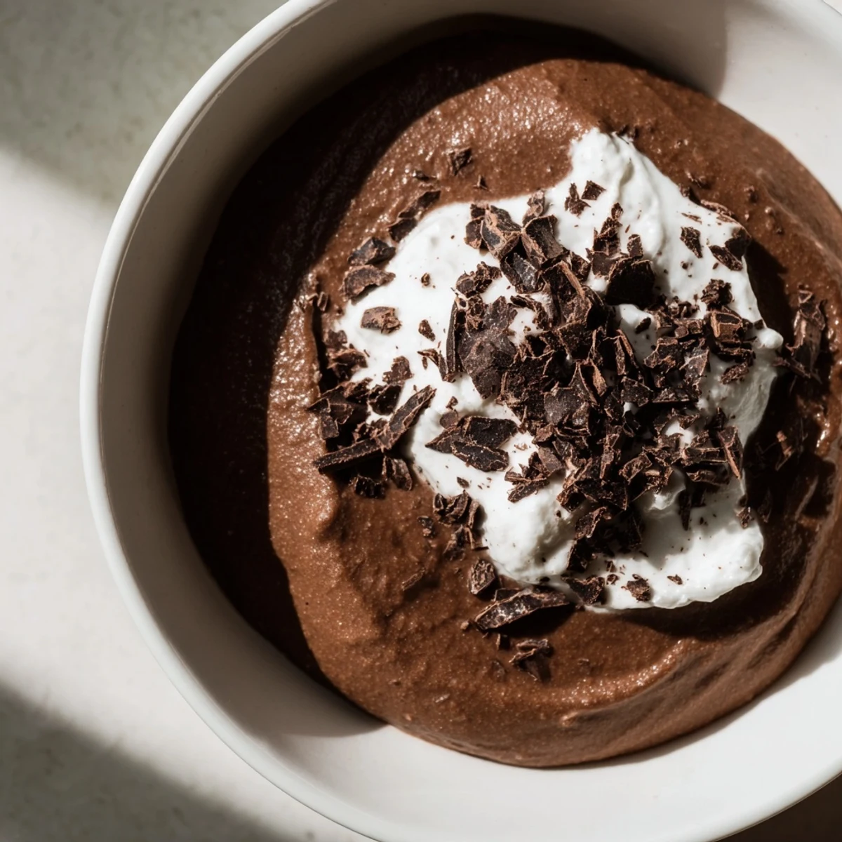Rich dark Chocolate Avocado Mousse layered with coconut whipped cream and fresh berries for a healthy dessert.