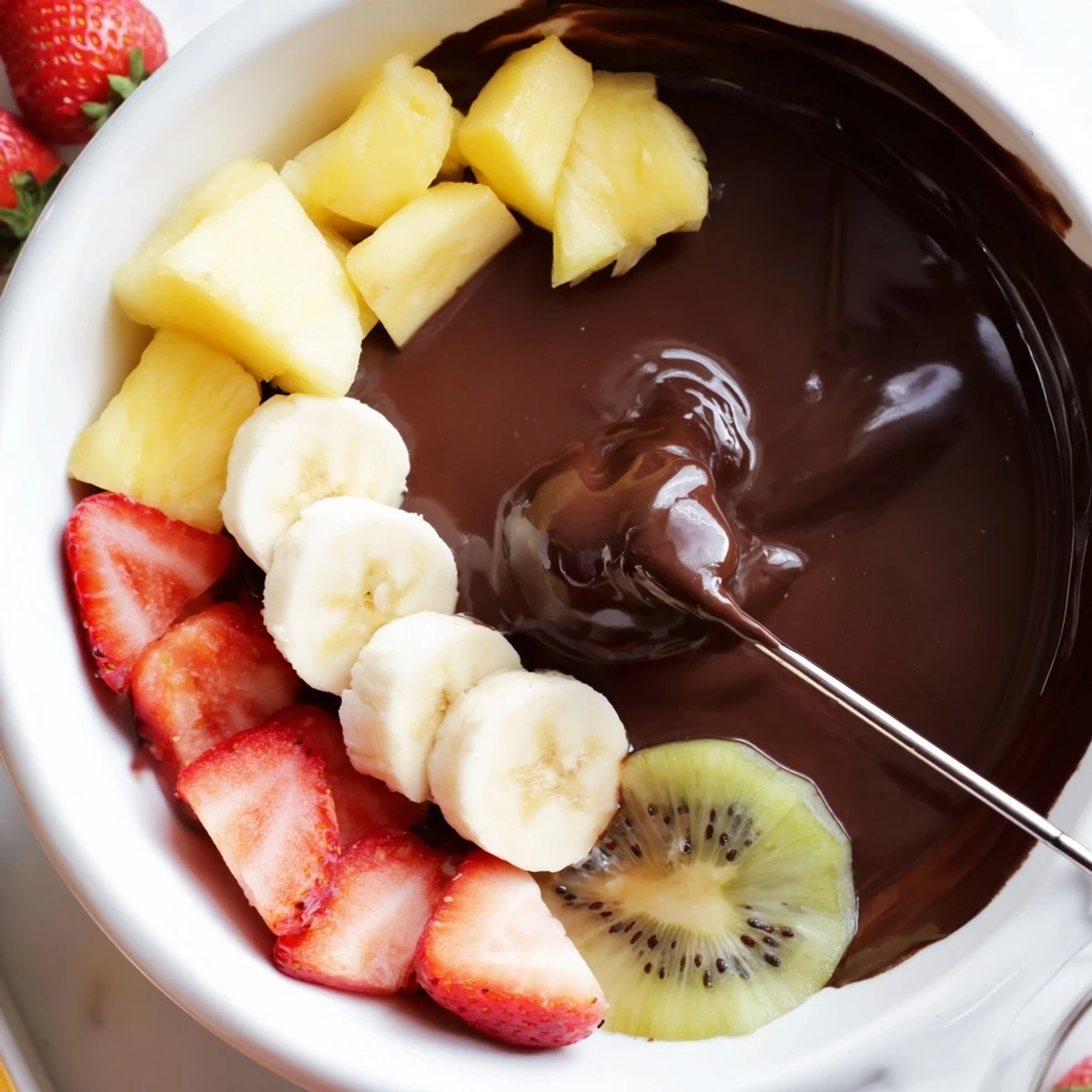 A close-up of Valentine Chocolate Fondue with Fresh Fruit, showing glossy melted chocolate and colorful sliced strawberries, bananas, and kiwi arranged for easy dipping.  