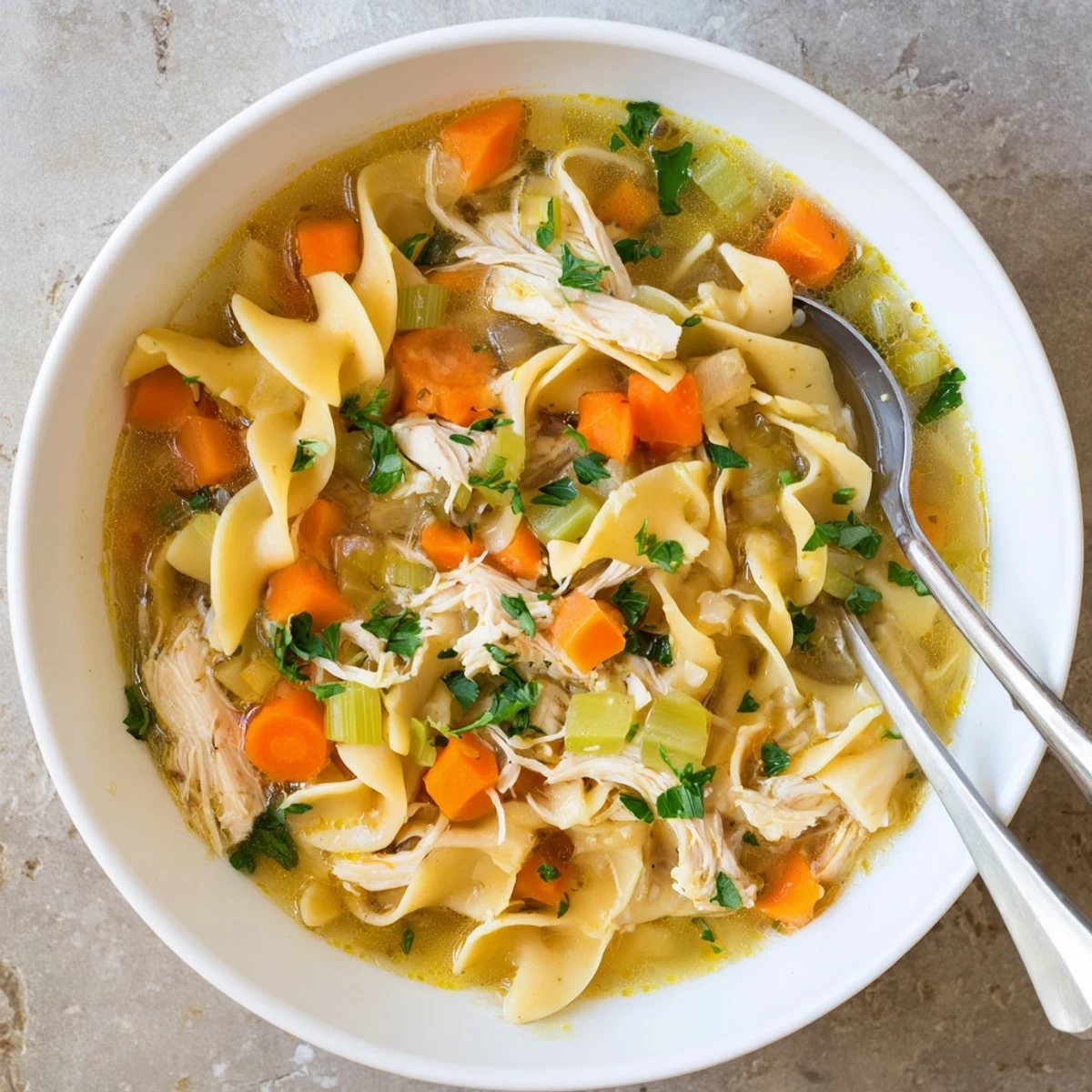 A steaming bowl of Chicken Noodle Soup with Homemade Noodles, featuring tender shredded chicken, carrots, celery, and silky fresh noodles in a golden broth.