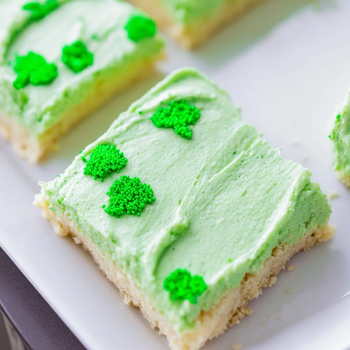 Freshly baked Shamrock Cookie Bars with vibrant green frosting, sliced into squares for easy serving at parties.