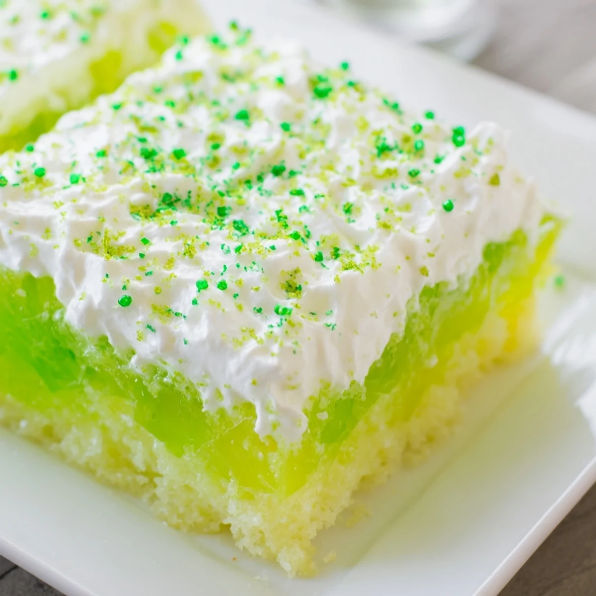Chilled St. Patricks Day Lime Poke Cake squares garnished with lime zest, ready for a festive dessert buffet.