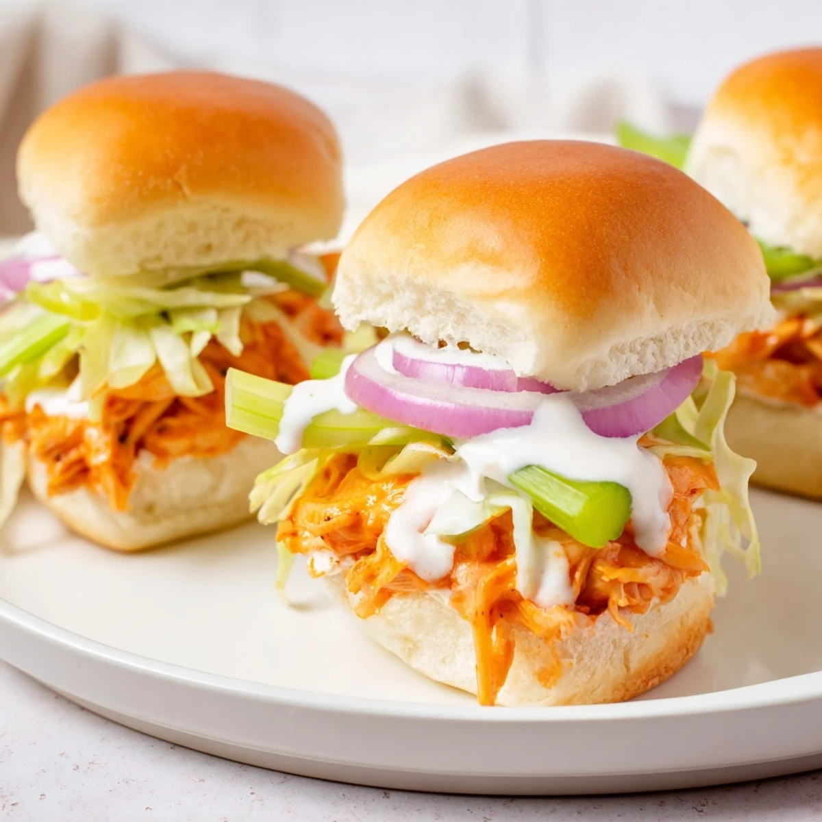Juicy Buffalo Chicken Sliders with Ranch Dressing feature tangy shredded chicken, fresh veggies, and creamy ranch drizzled over golden toasted buns.