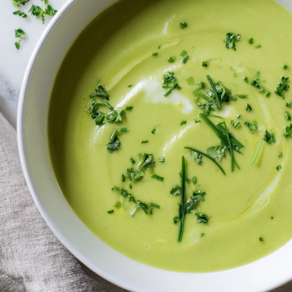 Spring-inspired Creamy Roasted Asparagus and Pea Soup shows velvety texture and a drizzle of cream.