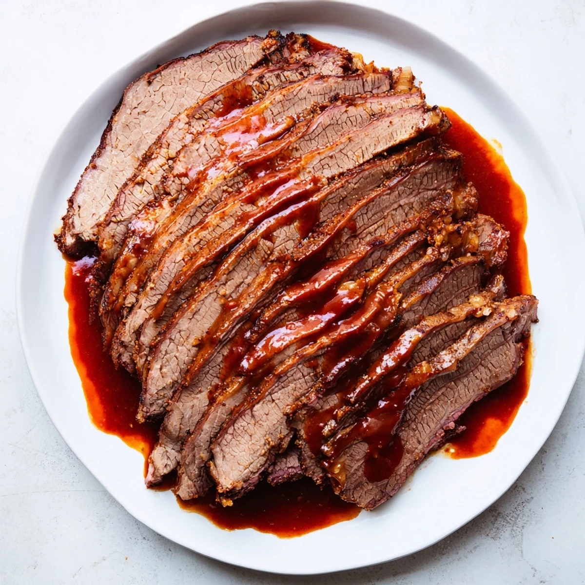 A platter of slow cooked beef brisket with smoky BBQ sauce, garnished with pickles and perfect for gatherings.