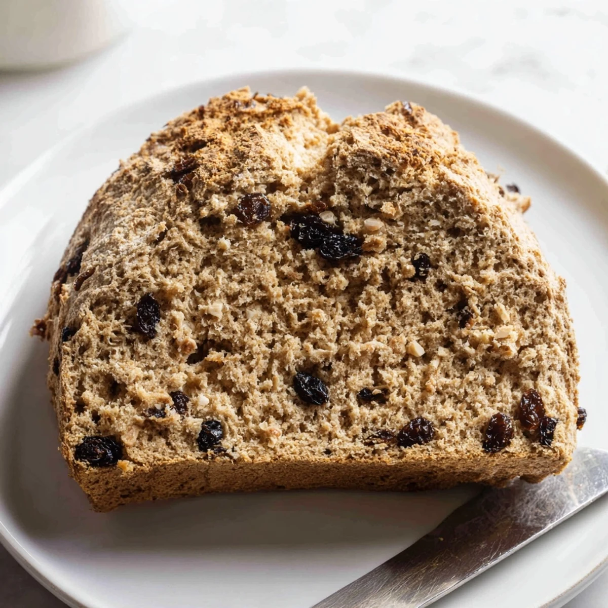 Freshly baked whole wheat Irish soda bread with currants cooling on a wire rack, steam rising gently.  
