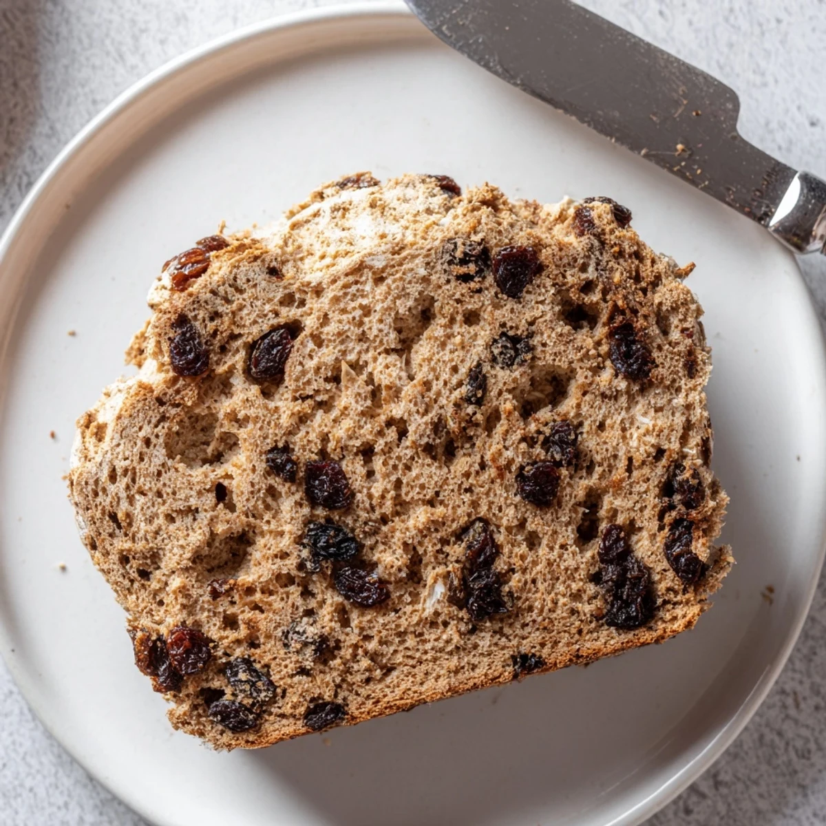 Golden-brown whole wheat Irish soda bread with currants served warm, with butter and jam on the side.