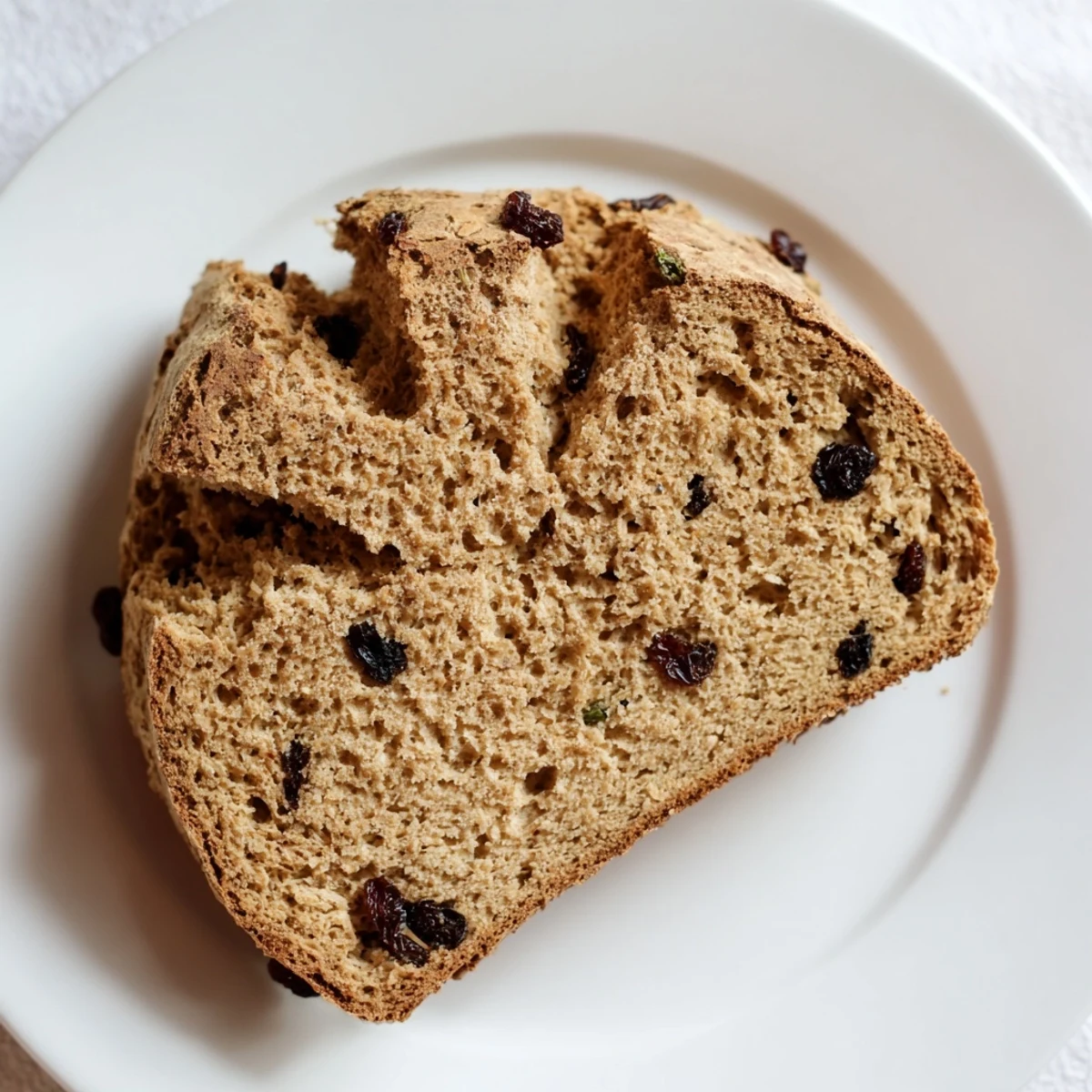 Freshly baked Whole Wheat Irish Soda Bread with Currants cooling on a wooden board, showcasing its rustic golden crust.