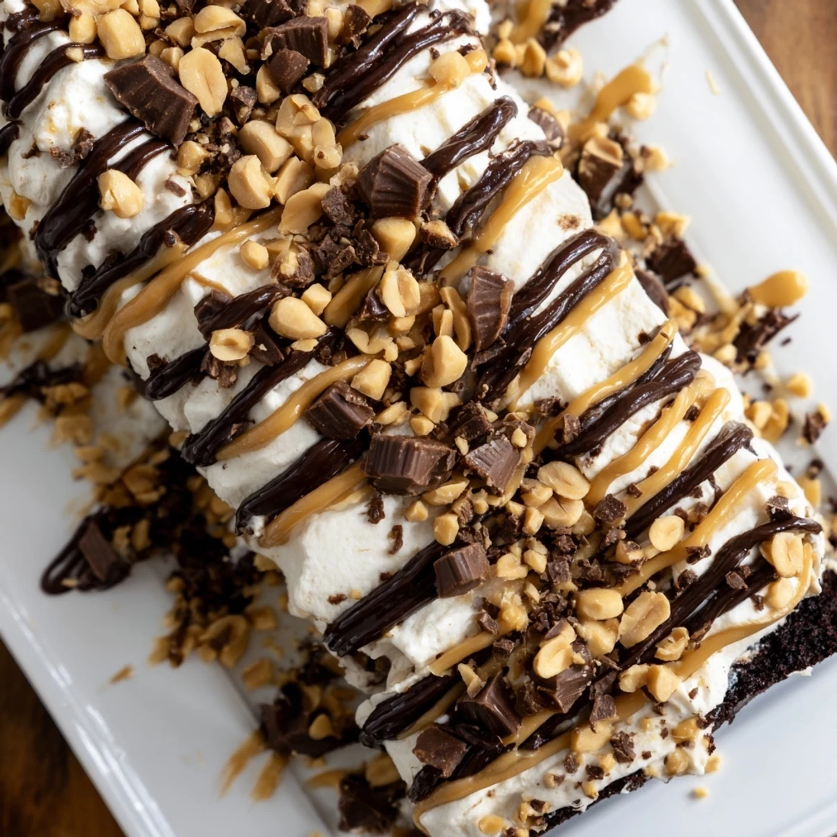 Served chilled, this layered Chocolate Peanut Butter Poke Cake features chopped peanuts and chocolate drizzle.