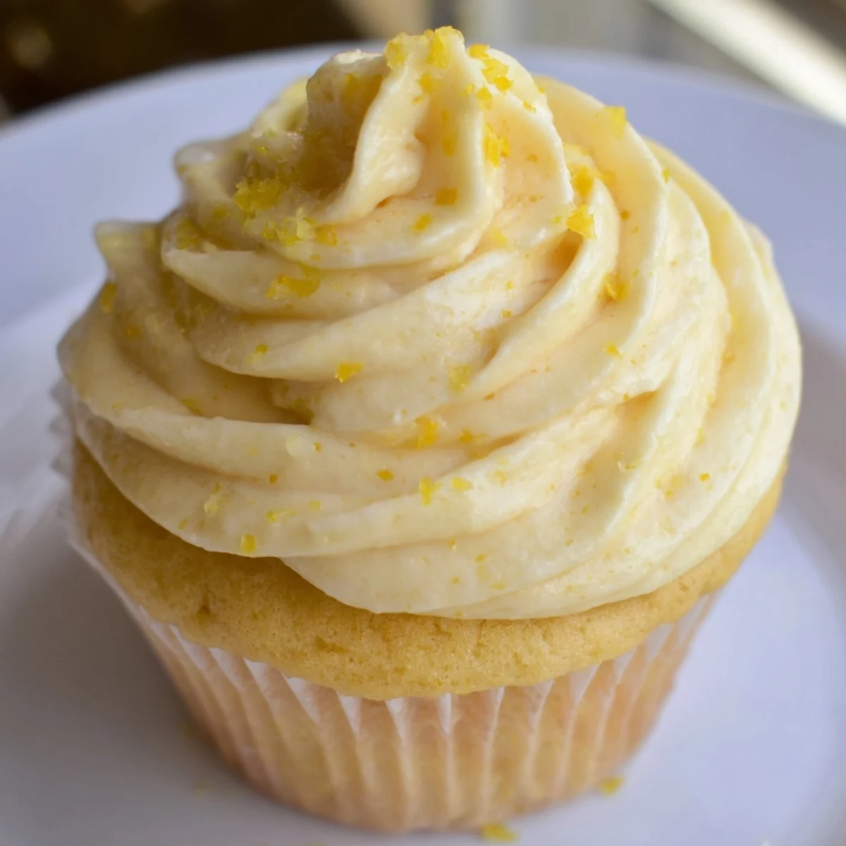 A close-up of Limoncello Cupcakes, each topped with swirls of tangy lemon buttercream and a dusting of fresh zest.