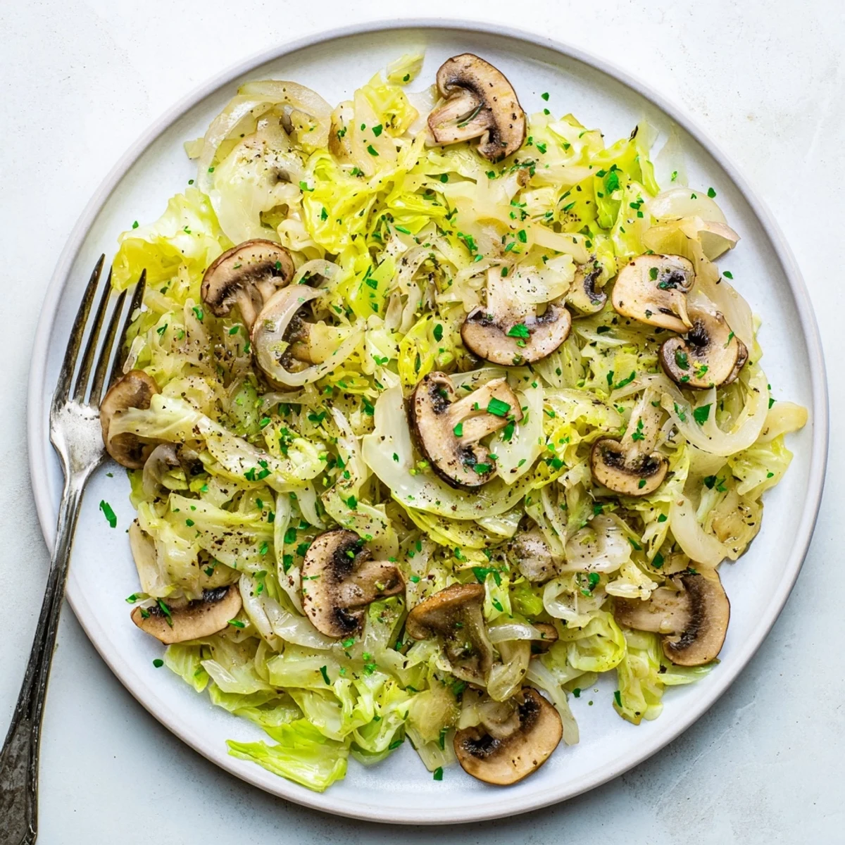 Steaming vegetarian cabbage mushroom sauté is served alongside a bowl of fluffy quinoa for a light, hearty meal.  