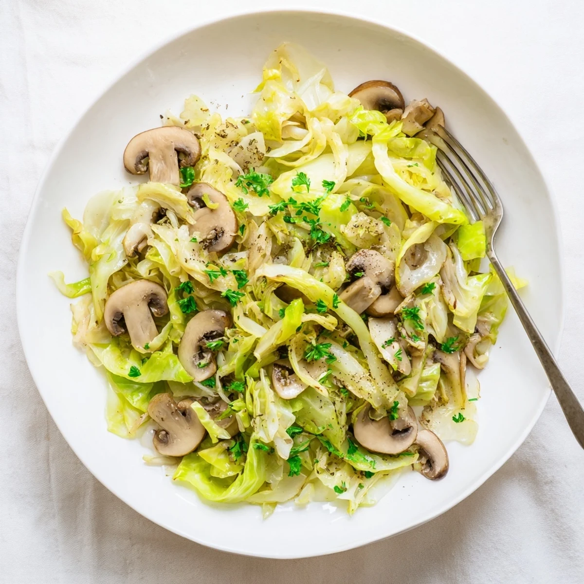 A skillet of vibrant vegetarian cabbage mushroom sauté showcases tender cabbage leaves and browned cremini mushrooms.