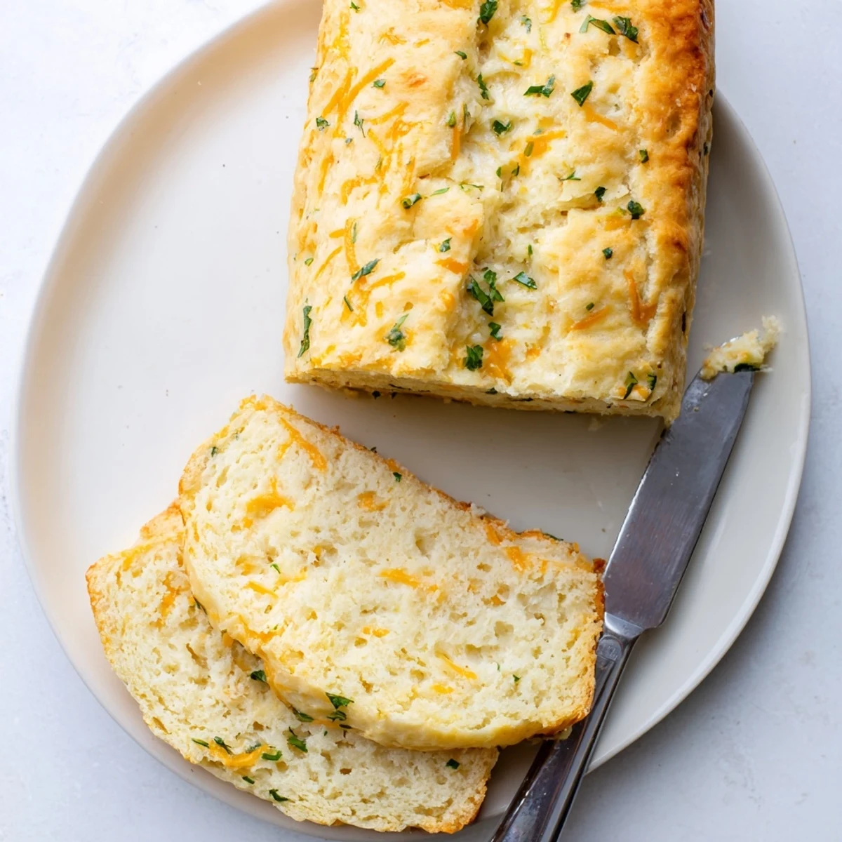 A slice of Red Lobsters Cheddar Bay Biscuit Loaf showing melted sharp cheddar and fresh parsley on buttery bread.