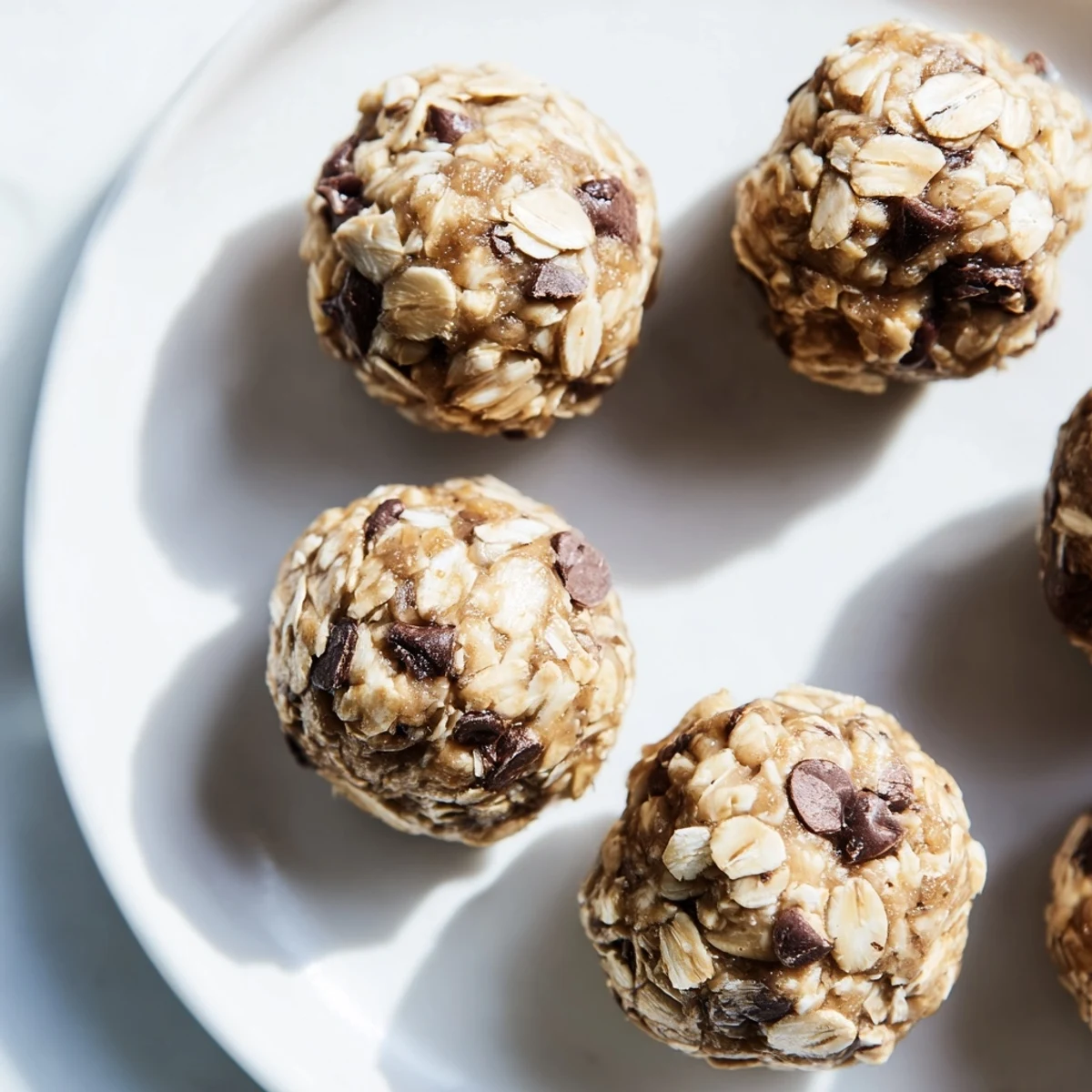 Freshly rolled Mint Chocolate Chip Protein Balls on a wooden board, with a glass of milk nearby for a post-workout snack.