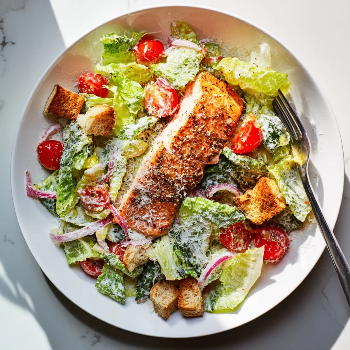 A close-up view of a delicious Salmon Caesar Salad featuring creamy homemade dressing and savory Parmesan cheese.