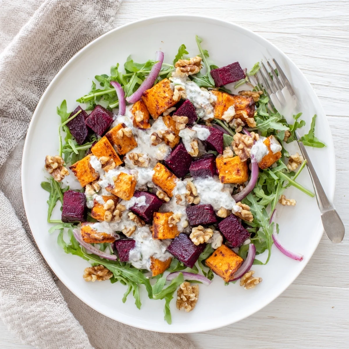Platter of vegetarian roasted beet salad with sweet potato chunks, red onion, and luscious Greek yogurt dressing for a hearty meal