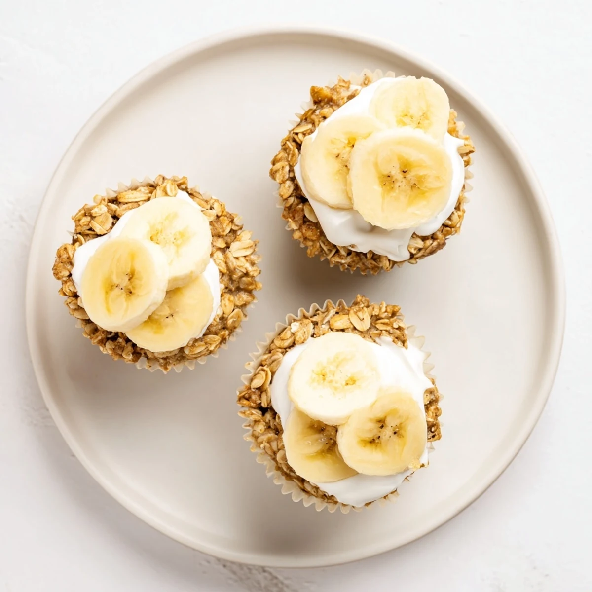Golden banana baked oatmeal cups topped with creamy Greek yogurt and fresh sliced banana