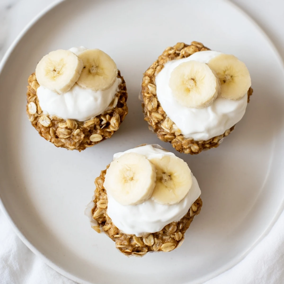 Portable breakfast muffins made with mashed bananas, rolled oats, and Greek yogurt topping