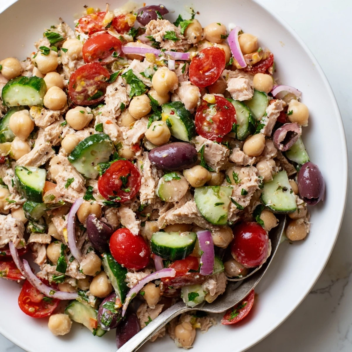 Colorful hearty tuna and garbanzo bean salad plated with fresh vegetables and lemon-herb dressing