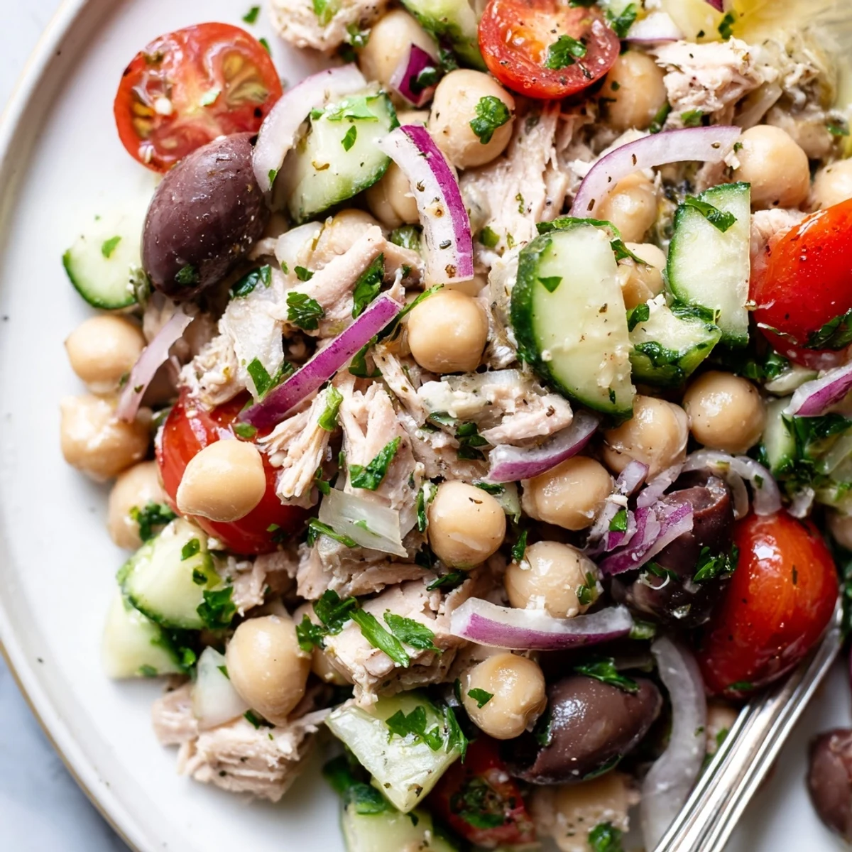 Mediterranean-style bowl featuring chunky tuna, creamy chickpeas, crisp tomatoes, and tangy olive oil dressing