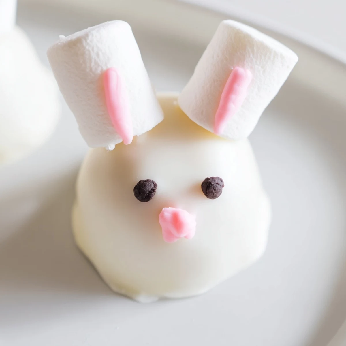 Adorable white chocolate bunny Oreo balls decorated with pink ears and fluffy marshmallow tails for Easter