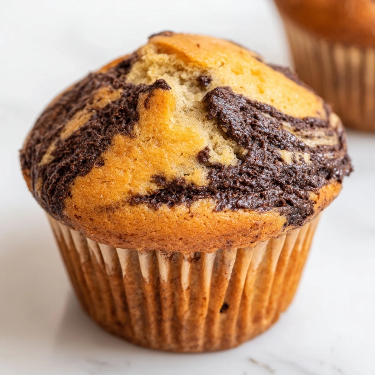 Golden Nutella banana muffins with swirls of chocolate hazelnut spread on a white plate