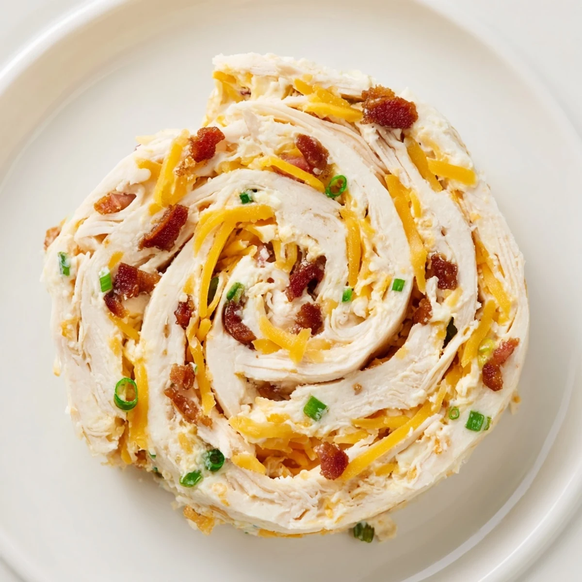 Platter of chilled crack chicken pinwheels featuring golden tortillas wrapped around seasoned chicken filling
