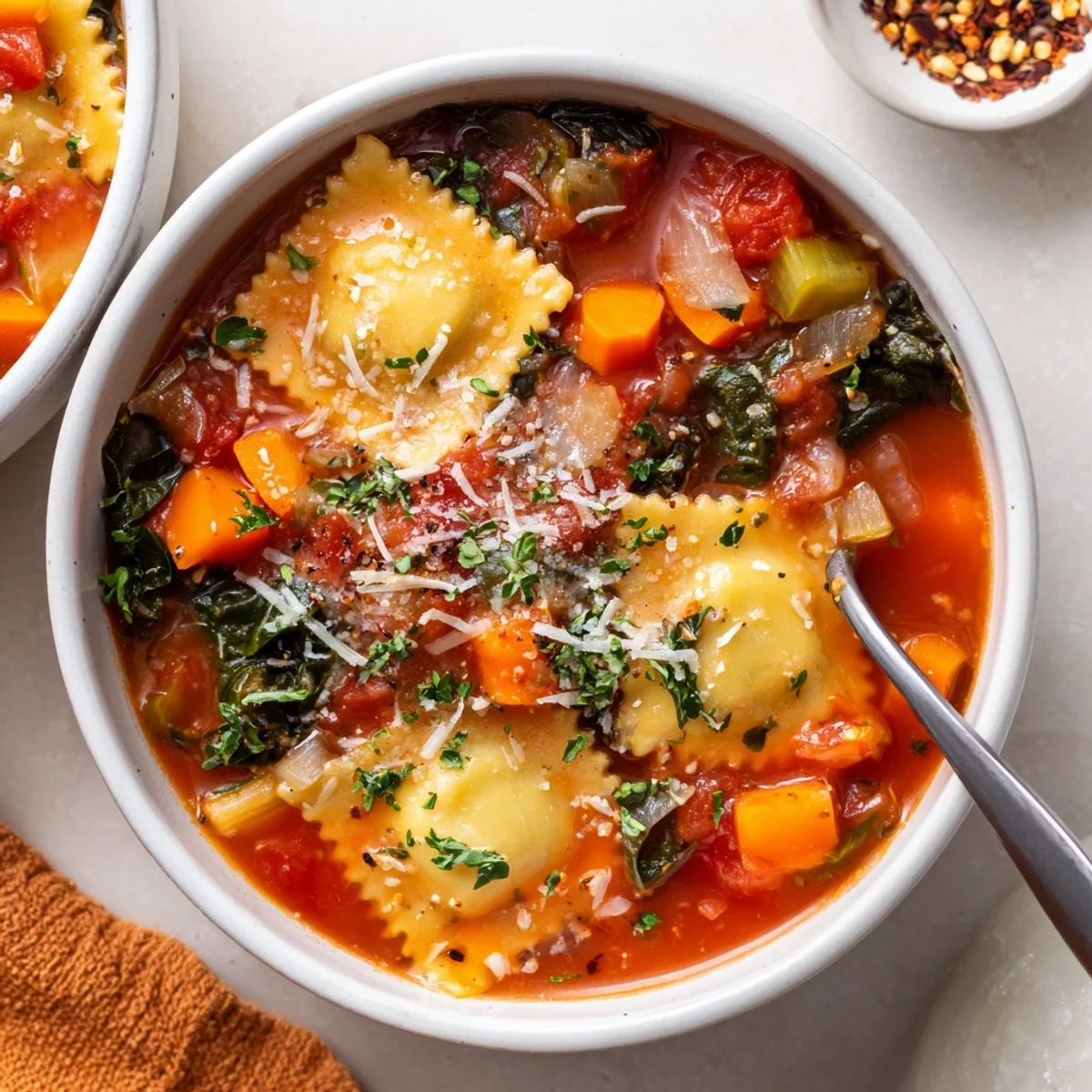 Savory Easy Tuscan Ravioli Soup with floating pasta and wilted spinach in rustic bowl