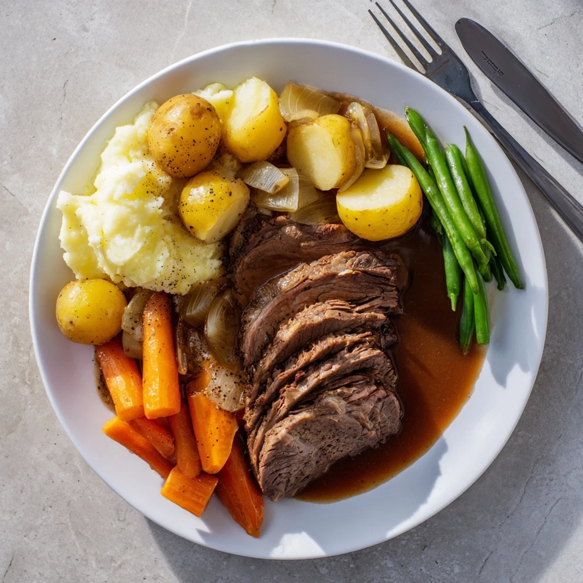 Golden brown Southern Style Pot Roast with tender beef and rich brown gravy served on white plate