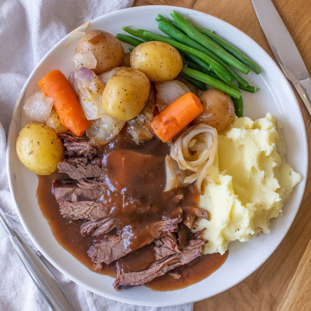 Fork-torn Southern Style Pot Roast plate with fluffy mashed potatoes and buttery green beans on rustic table