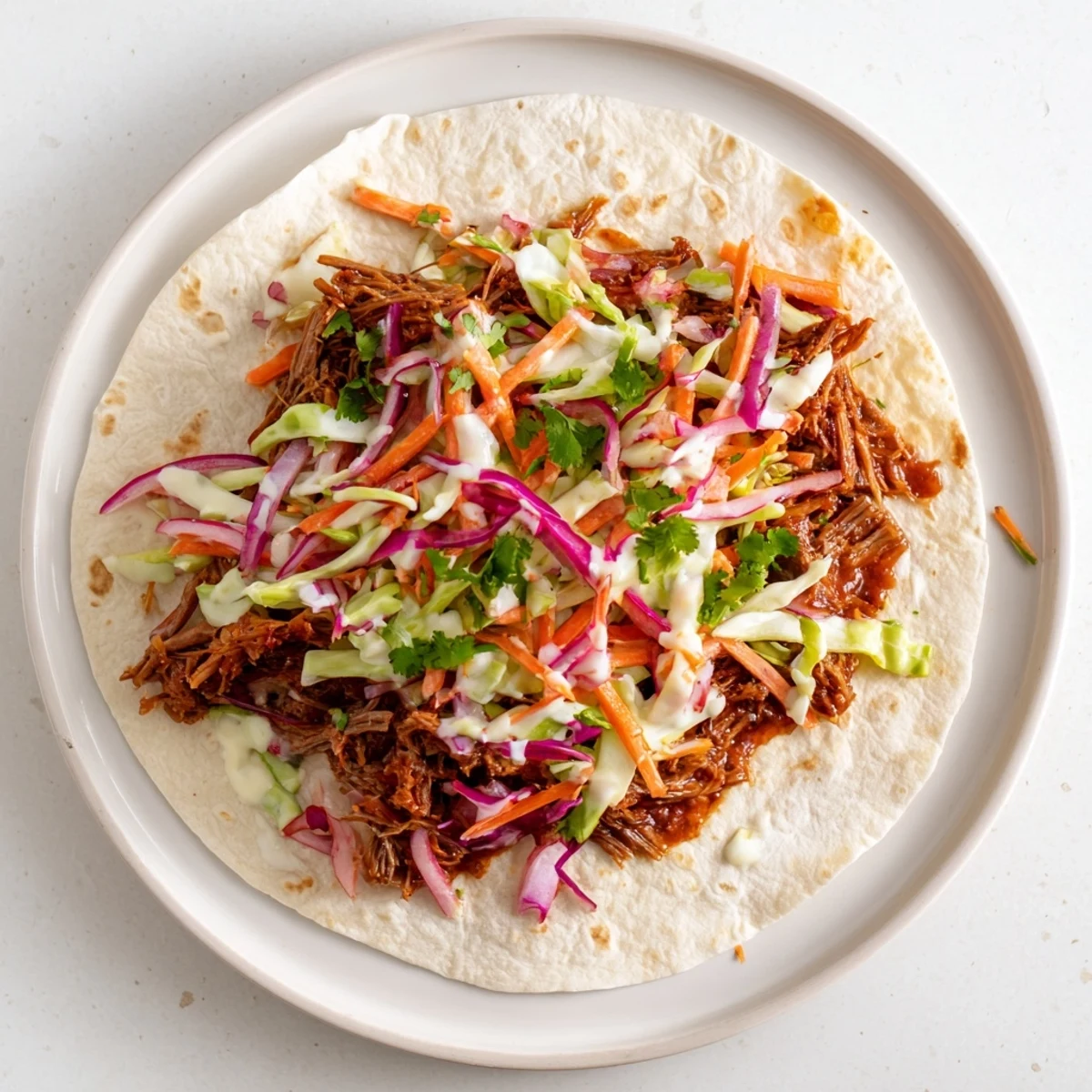 Flour tortilla wrap filled with tender sweet smoky BBQ pulled beef and colorful crunchy slaw