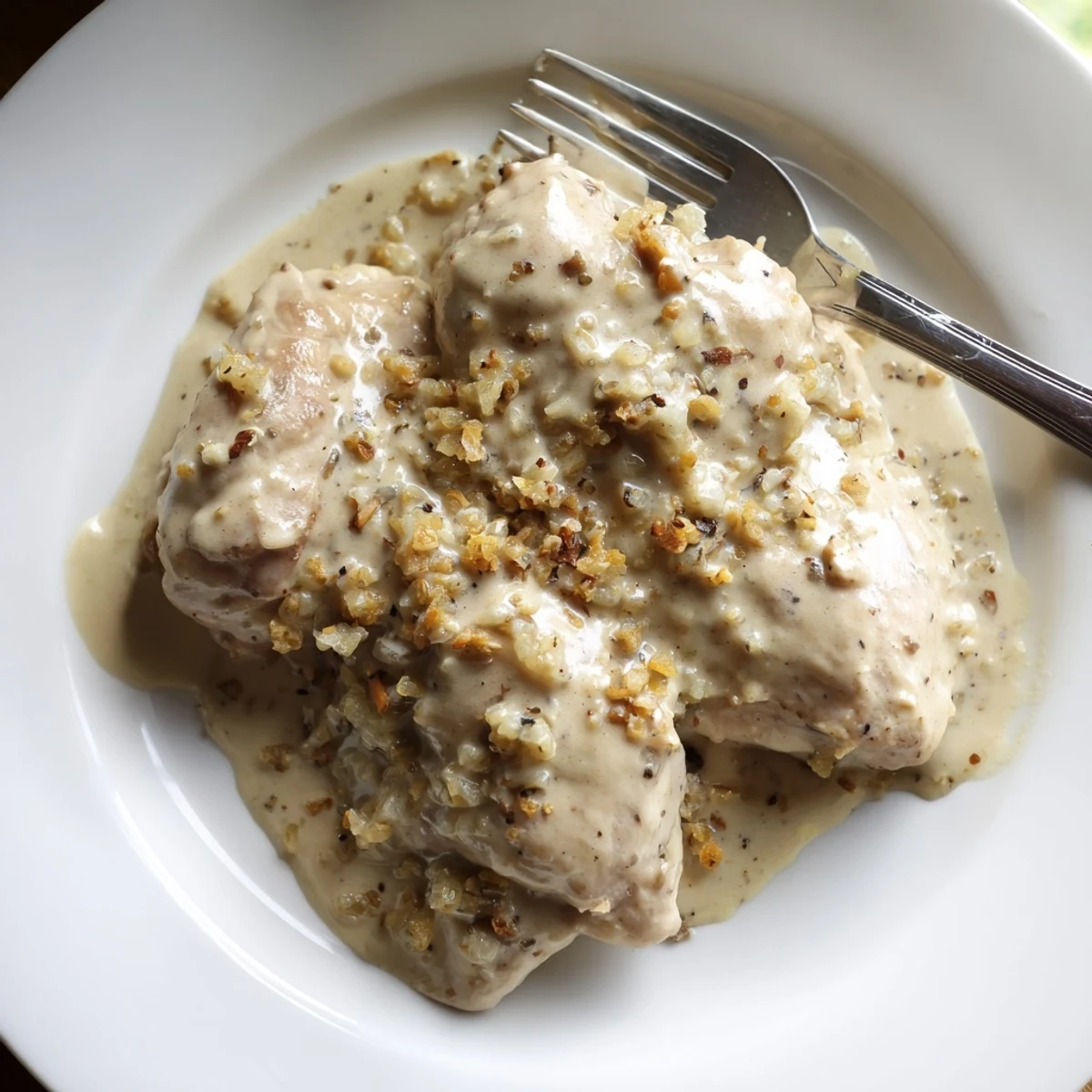 Golden brown chicken thighs swimming in a rich, creamy crockpot gravy sauce with herbs