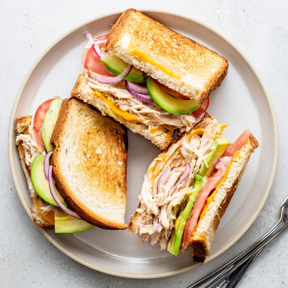 Golden brown chicken avocado melt sandwich with melted cheese oozing from toasted sourdough bread slices