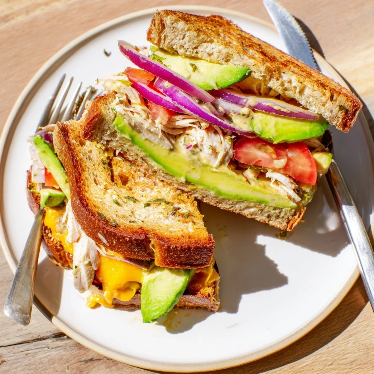 Hot grilled chicken avocado melt sandwich cut diagonally revealing layers of creamy avocado and melted cheese