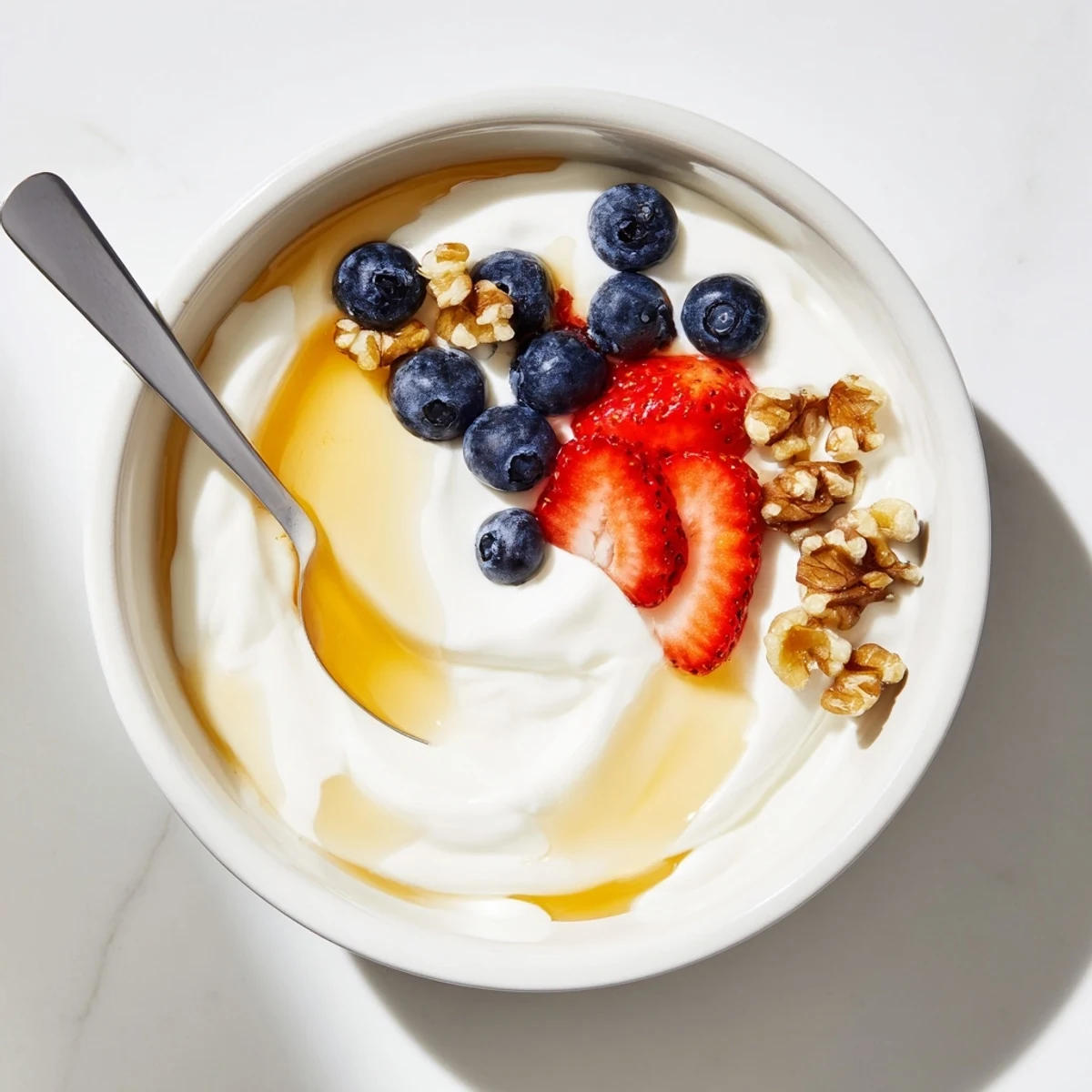 Creamy homemade Greek yogurt topped with fresh berries and honey in a white bowl