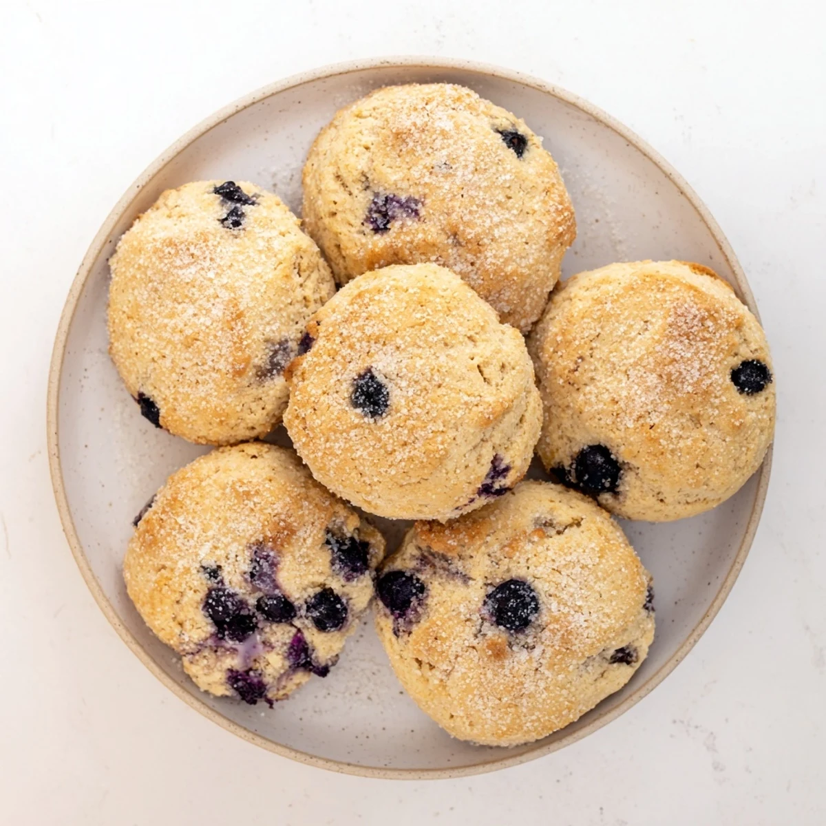 Flaky homemade blueberry biscuits on a white plate melting butter