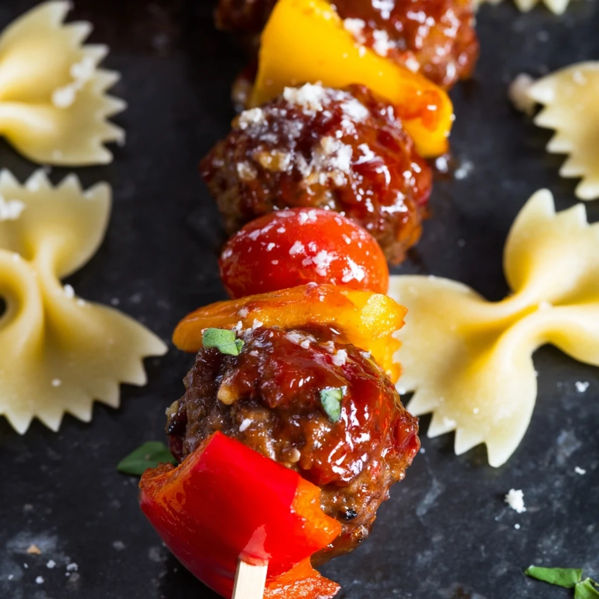 Juicy cocktail meatballs alternated with bowtie pasta and crisp bell peppers on wooden skewers