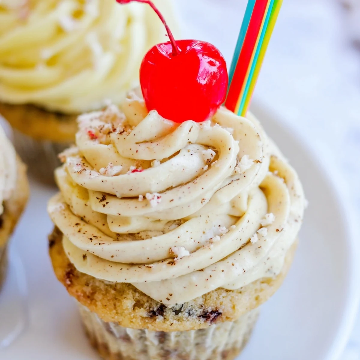 Moist banana milkshake cupcakes topped with fluffy vanilla frosting and bright red maraschino cherries