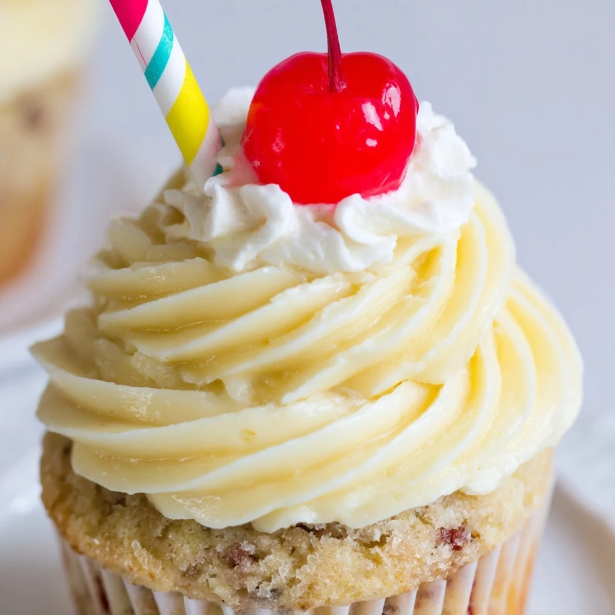Golden banana milkshake cupcakes with creamy swirled frosting served on a rustic white platter