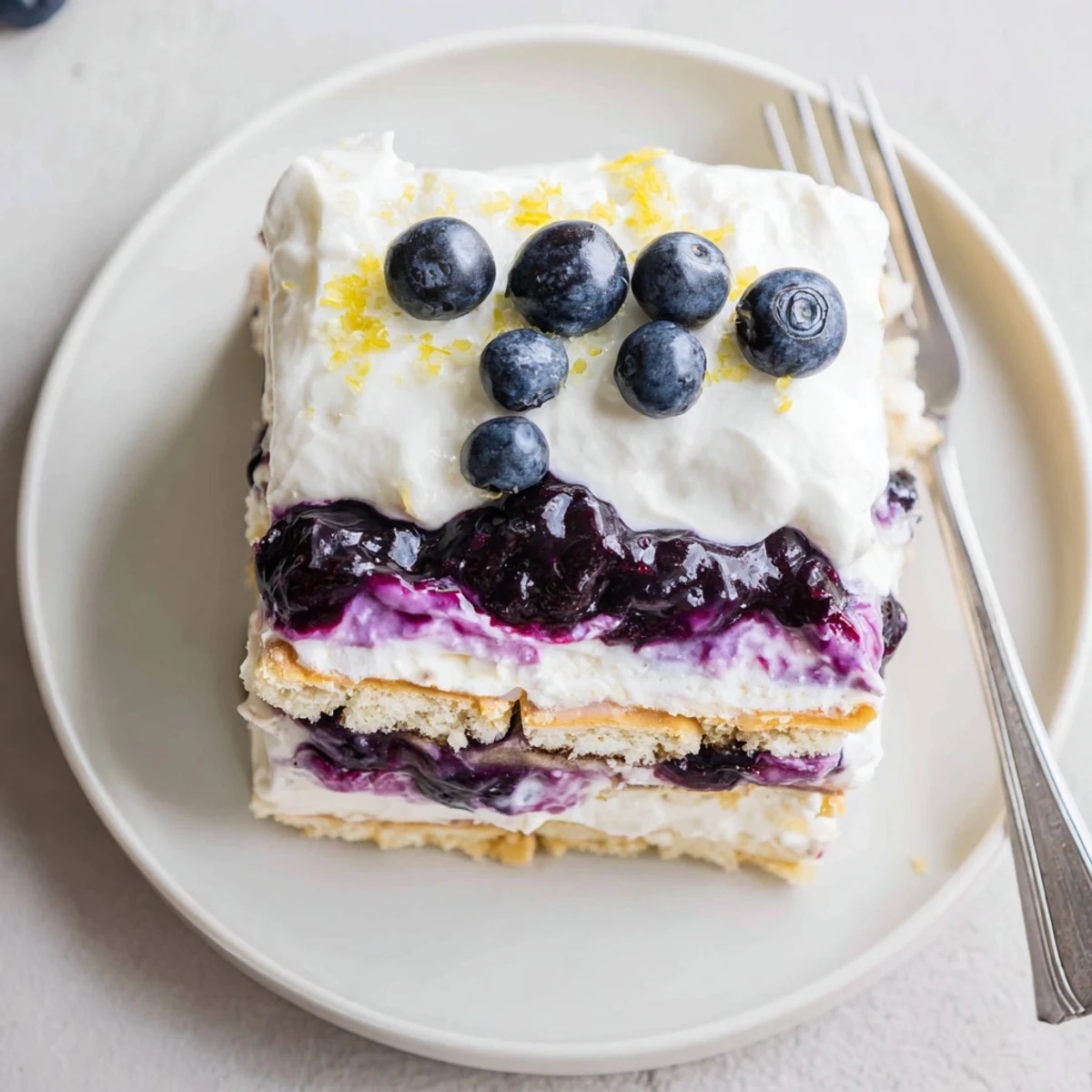 Sliced lemon blueberry lasagna with swirled purple berry sauce and fluffy cream layers