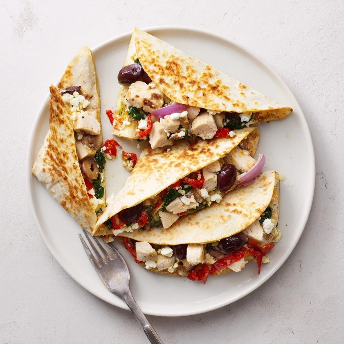 Crispy Greek chicken quesadillas featuring juicy marinated meat, Mediterranean vegetables, and melted mozzarella and feta cheese