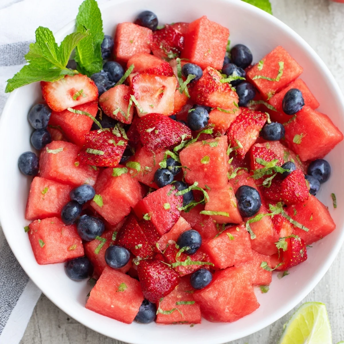 Summer watermelon recipe featuring colorful mixed berries, fresh mint garnish, and citrus honey dressing on white plate