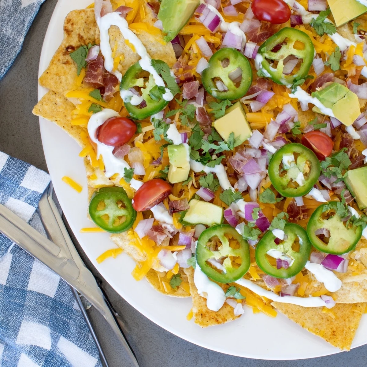 Platter of tuna nachos deluxe topped with colorful vegetables, shredded cheese, and tangy jalapeño crema