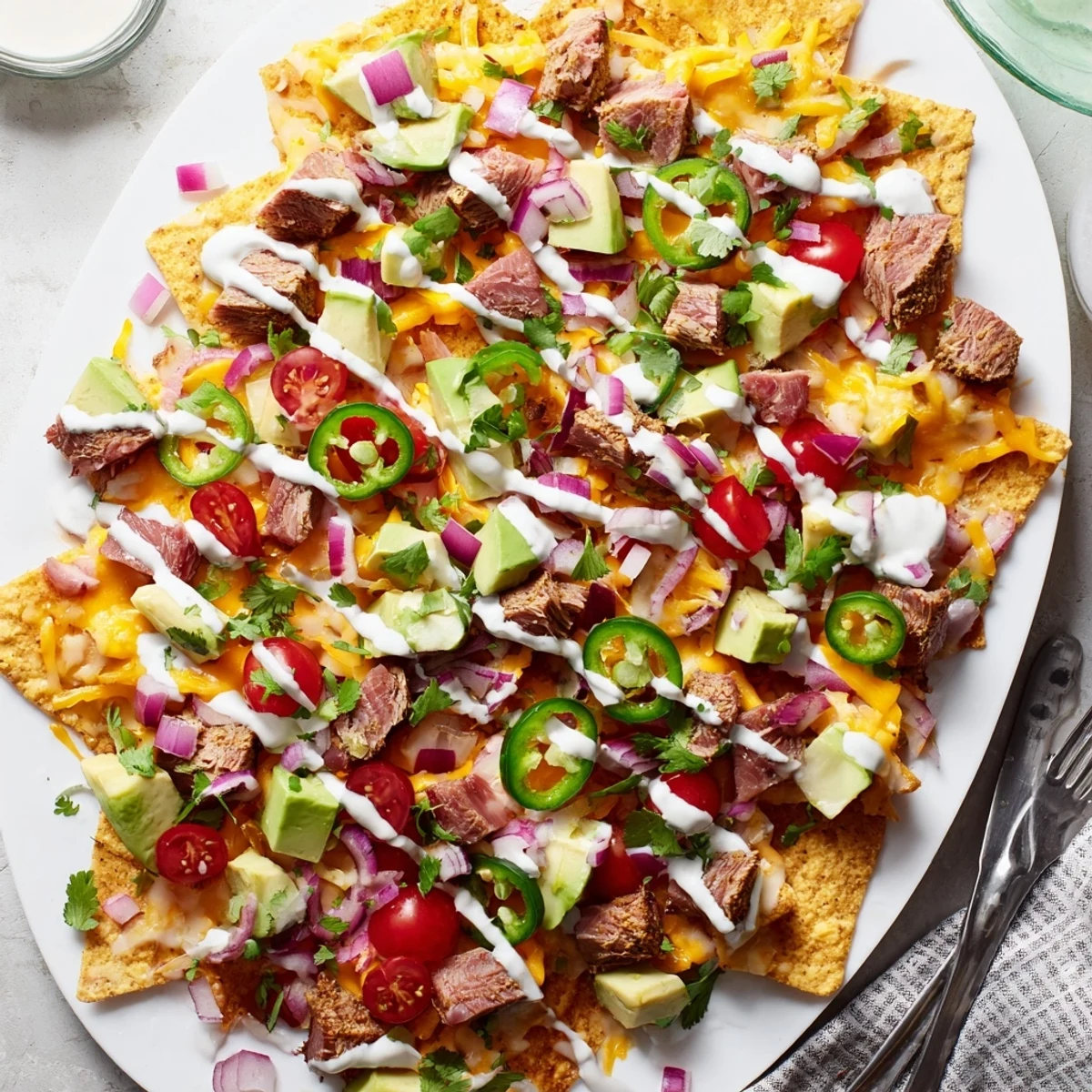 Golden tuna nachos deluxe featuring melty cheese, vibrant tomatoes, red onion, and creamy lime sauce